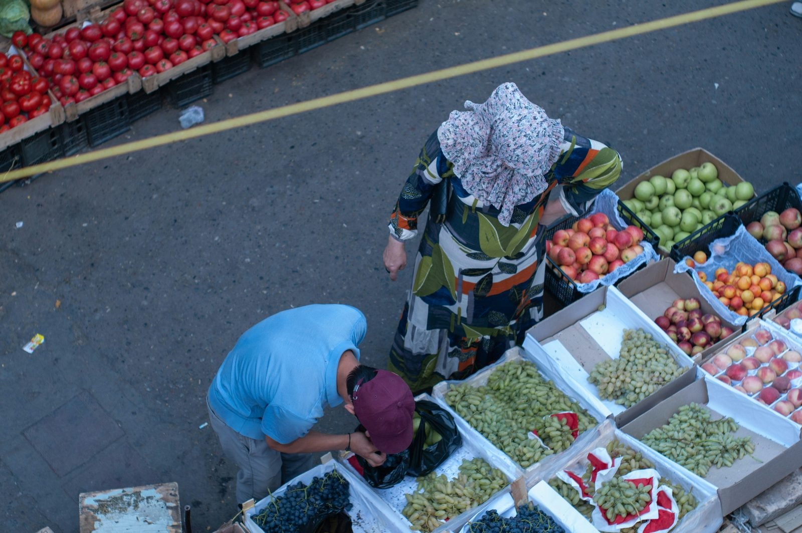 Clienti che comprano frutta e verdura ai banchi del bazar Chorsu di Tashkent