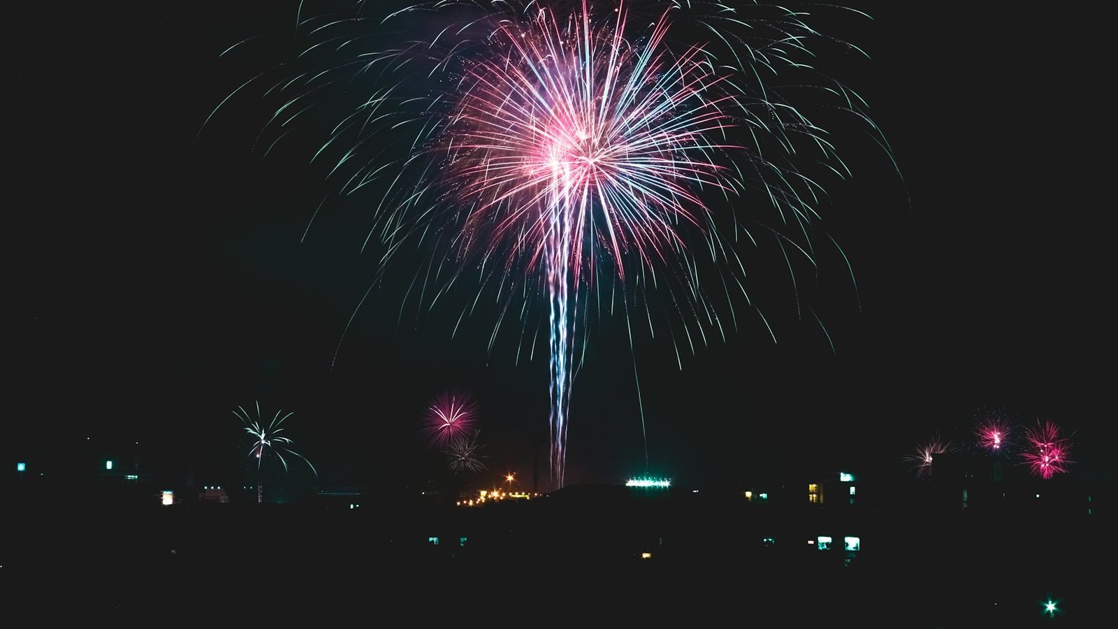 Fuochi d'artificio rosa e azzurri che esplodono nel cielo notturno di Bangkok