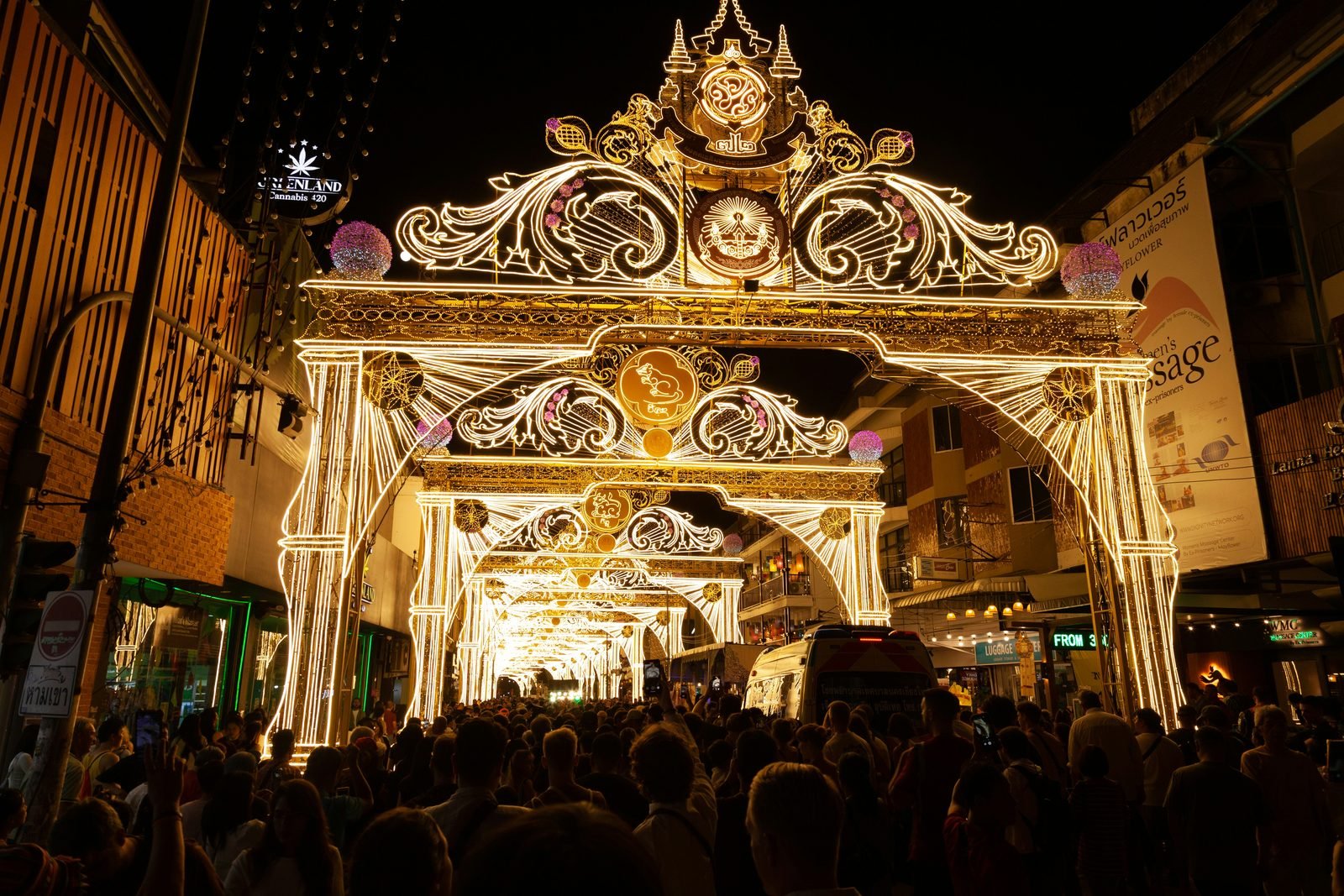 Un arco di luci dorate sopra una strada di Chiang Mai piena di gente durante la festa di Loy Krathong