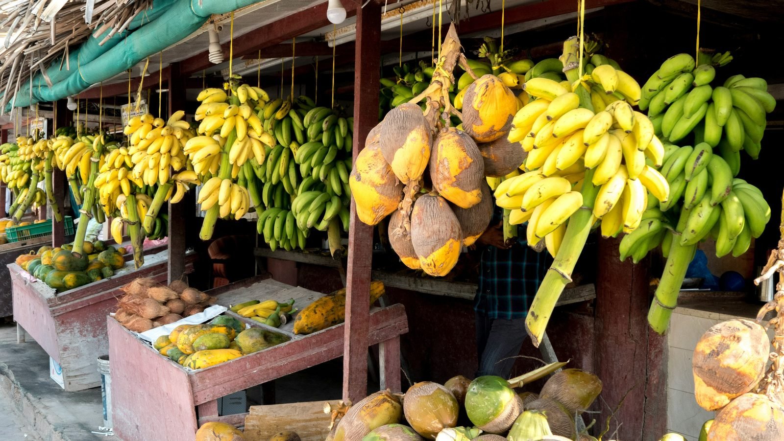 Bancarella di frutta tropicale a Salalah con caschi di banane, noci di cocco e papaye