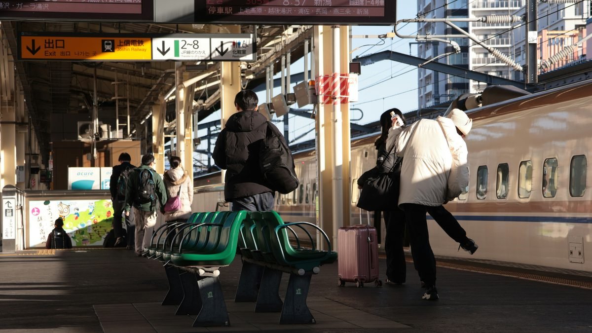 Viaggiatori con valigie sul binario di una stazione dello Shinkansen in Giappone