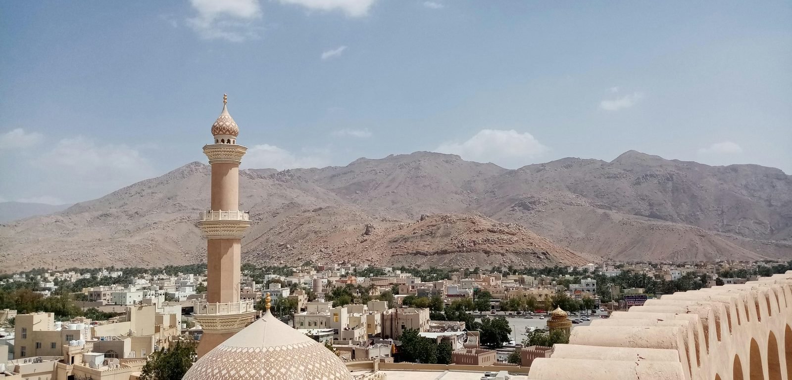 Nizwa vista dalle mura del forte, con il minareto, le case basse e le montagne Hajar