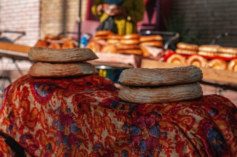 capodanno in oman Cosa mangiare in Uzbekistan: 12 piatti tipici e dove provarli (2026) Pani uzbeki rotondi (non) impilati su un telo ricamato al banco di un bazar di Tashkent