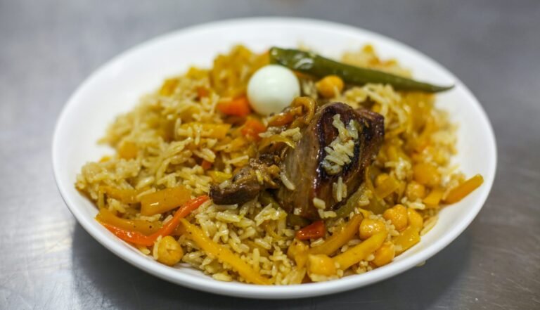 capodanno in oman Plov uzbeko: la ricetta originale passo passo Piatto di plov centroasiatico con riso, carote gialle e arancioni, ceci, carne, un uovo di quaglia e un peperoncino verde