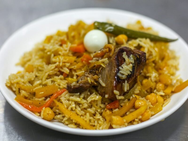 plov ricetta uzbeka Plov uzbeko: la ricetta originale passo passo Piatto di plov centroasiatico con riso, carote gialle e arancioni, ceci, carne, un uovo di quaglia e un peperoncino verde