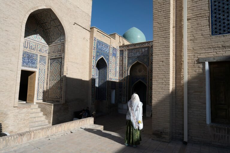 capodanno in oman Come vestirsi in Uzbekistan: donne, moschee e stagioni (2026) Una donna con il foulard bianco e la gonna lunga cammina tra i mausolei rivestiti di maiolica blu dello Shah-i-Zinda, a Samarcanda