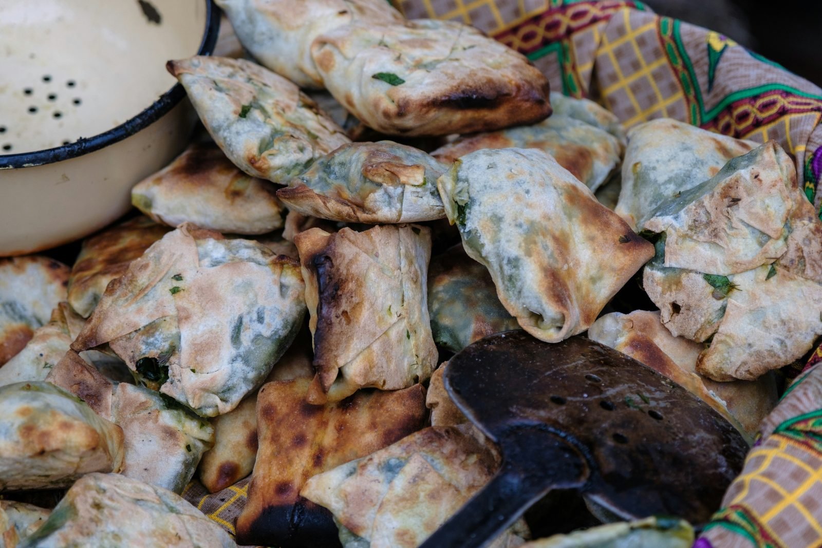 uzbekistan cosa mangiare Cosa mangiare in Uzbekistan: 12 piatti tipici e dove provarli (2026) Somsa cotte nel tandir con ripieno di erbe verdi, ammucchiate su un telo colorato nella regione di Fergana